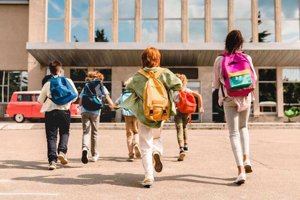 A group of schoolkids walking in the front door of their school