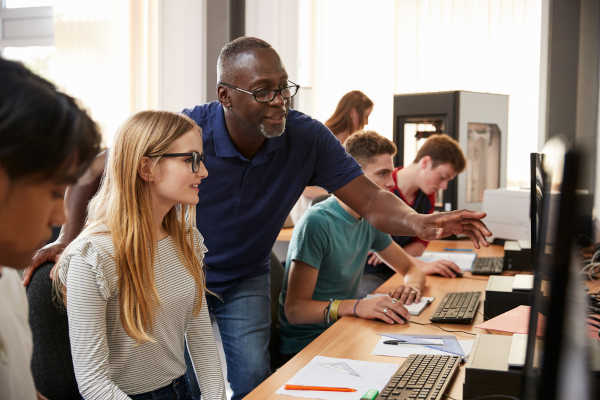 A teacher working with their student in a 3D printing lab