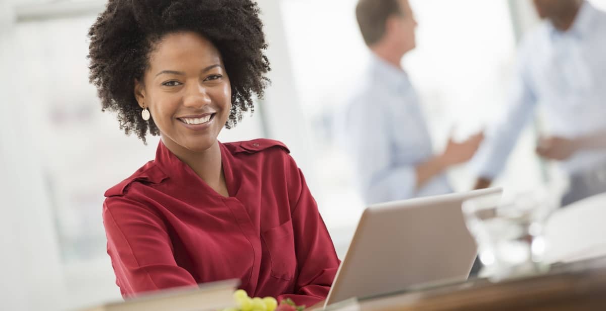 A smiling businessperson works on a laptop.