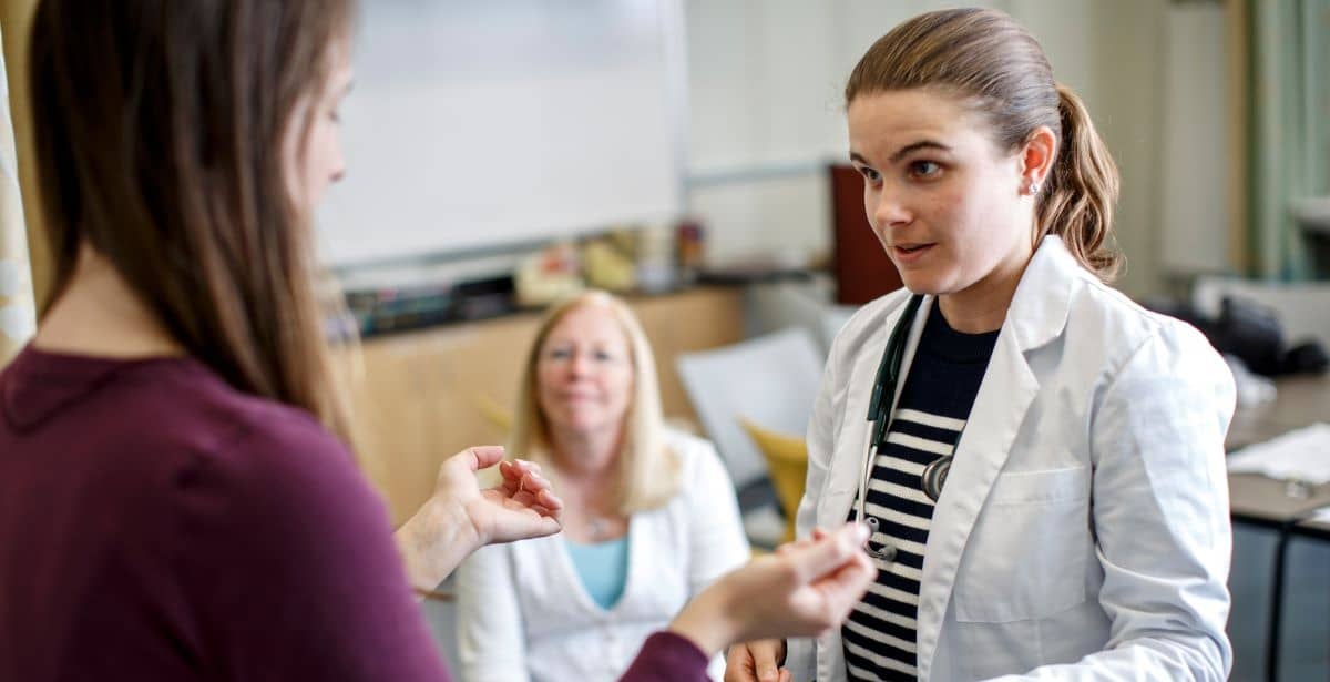 A care provider in a white coat talks with a patient.